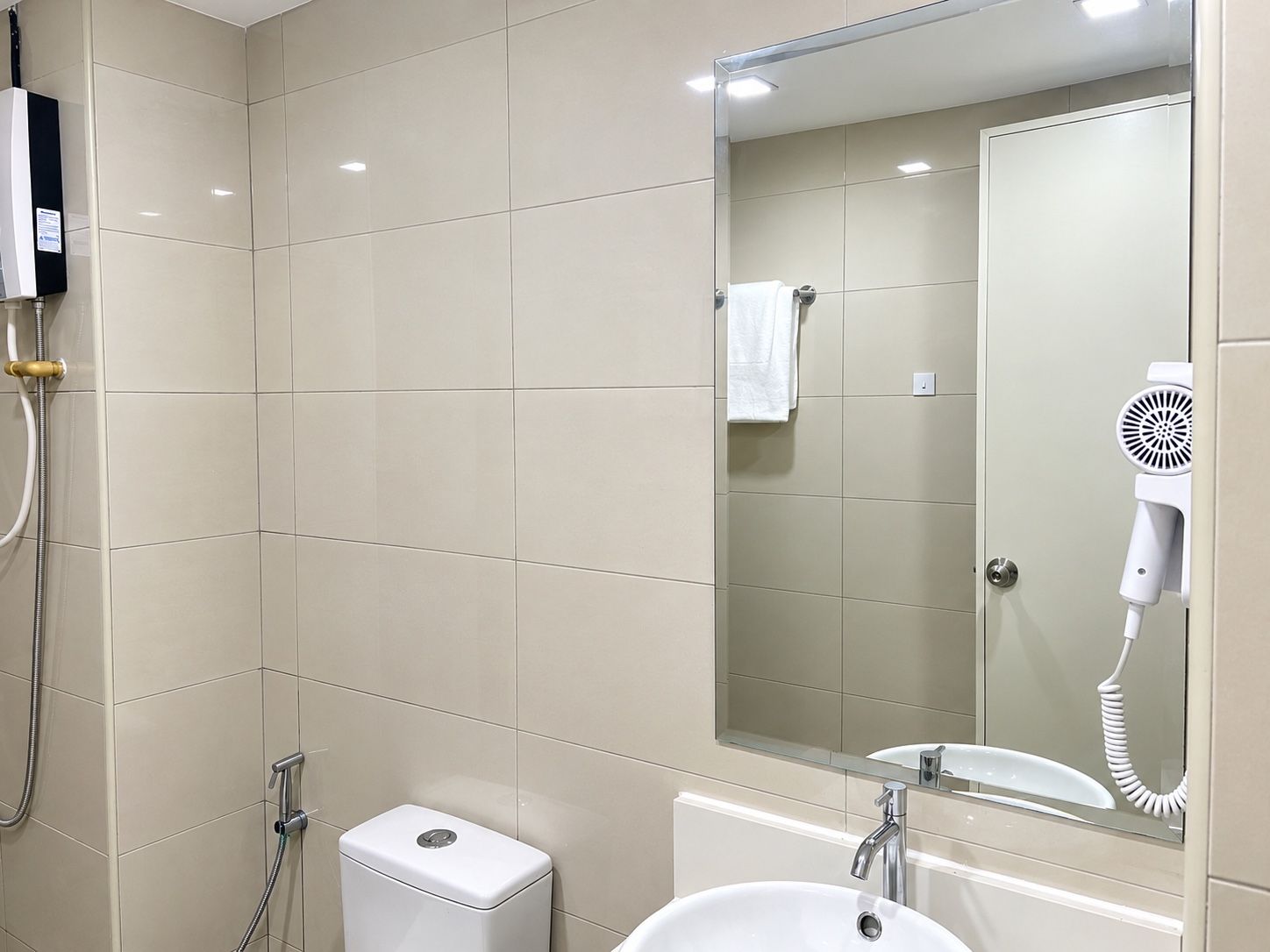 Ein Badezimmer mit Dusche, Toilette, Waschbecken und einem Föhn.