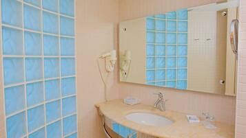 A bathroom with a sink, mirror, and a hairdryer on the wall.