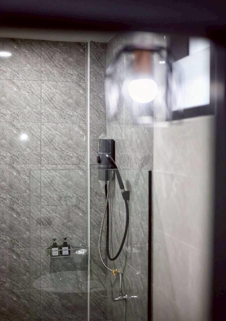 Une douche équipée d’un pommeau de douche à main et d’une cabine de douche en verre.