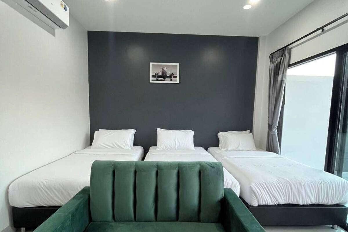Ein modernes Schlafzimmer mit einem großen Bett, einem grünen Sessel und einem Bild an der Wand.