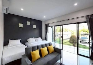 Una habitación de hotel con dos camas, un sofá y amplios ventanales.