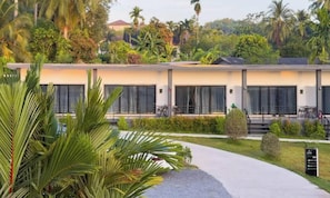 Un hotel moderno con techo plano, ventanas amplias y un sendero pavimentado que conduce a la entrada.