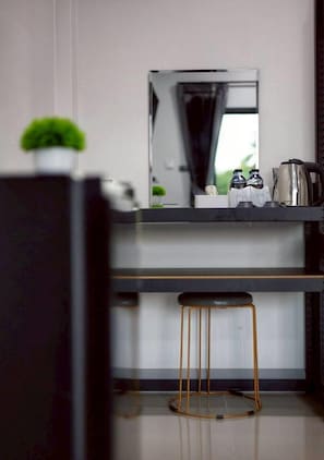 Una cocina moderna con encimera, espejo, máquina de café y un taburete.