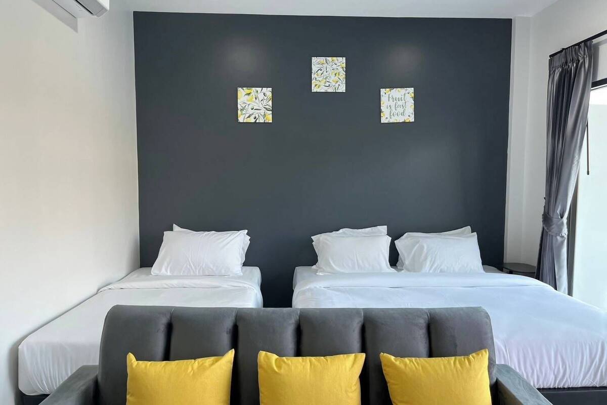Ein Hotelzimmer mit zwei Betten, einer dunklen Akzentwand und drei kleinen gerahmten Kunstwerken.