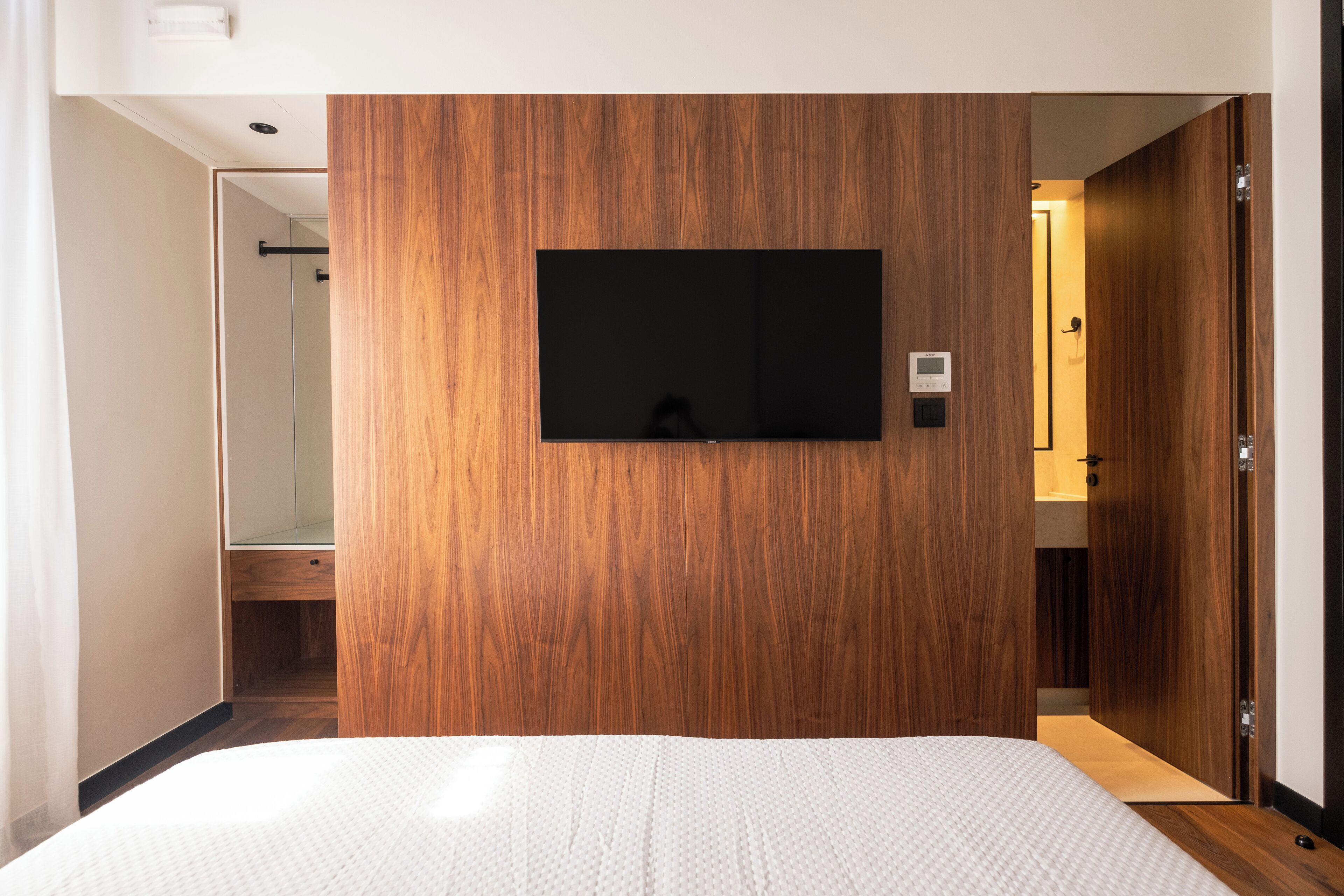 Une chambre d’hôtel avec un grand lit, un téléviseur fixé au mur et un mur recouvert de panneaux de bois.