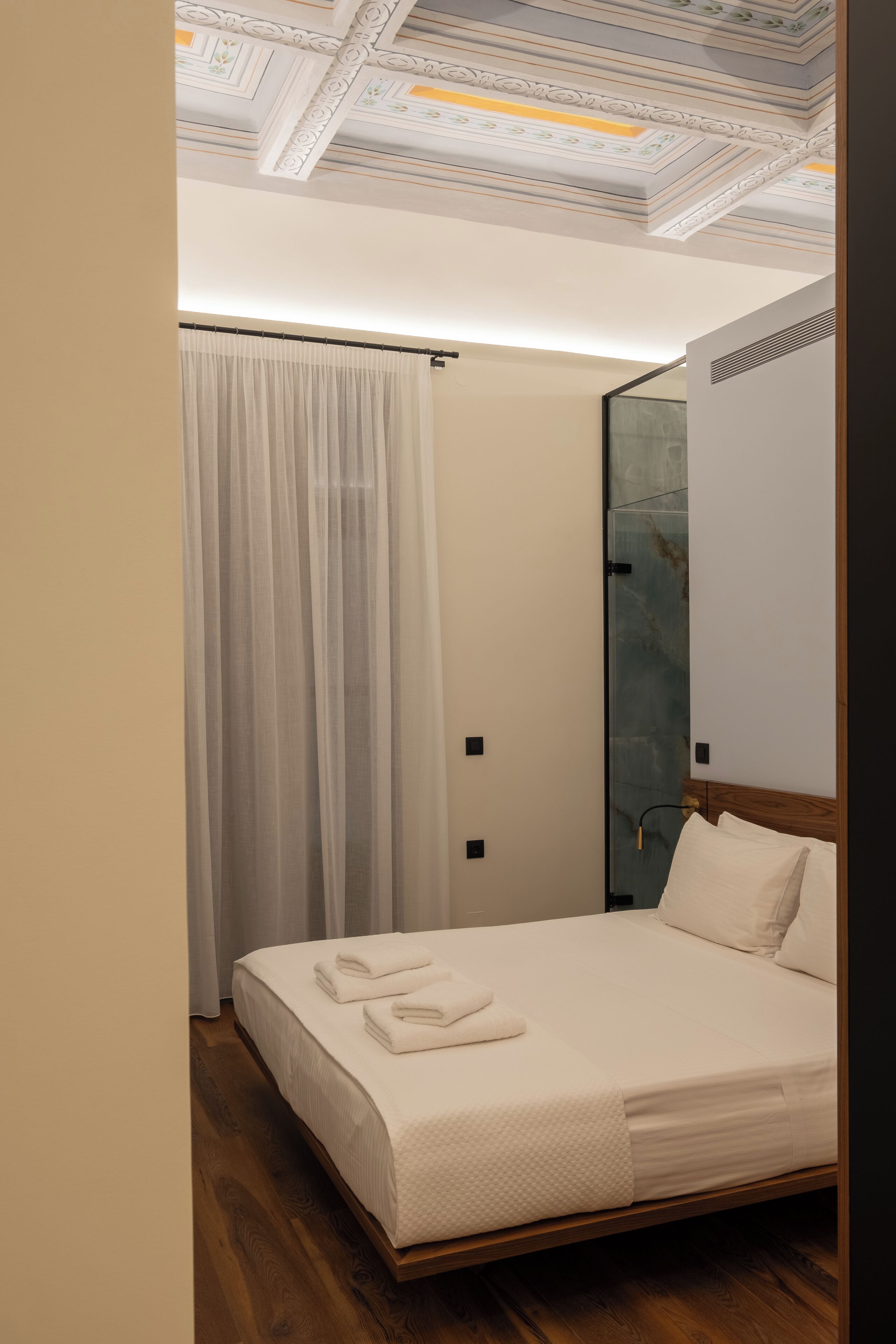 Un dormitorio moderno con una cama de madera, un espejo grande y un techo con diseños intrincados.
