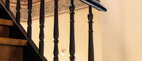 A wooden staircase with ornate balusters and a metal handrail.