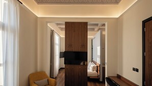 A hotel room with a wooden panel divider, a sofa, a bed, and a desk. - Bouquet Luxury Rooms (Chania)