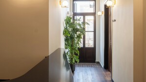 A hallway with a wooden floor, a potted plant, and a door with a window. - Bouquet Luxury Rooms (Chania)