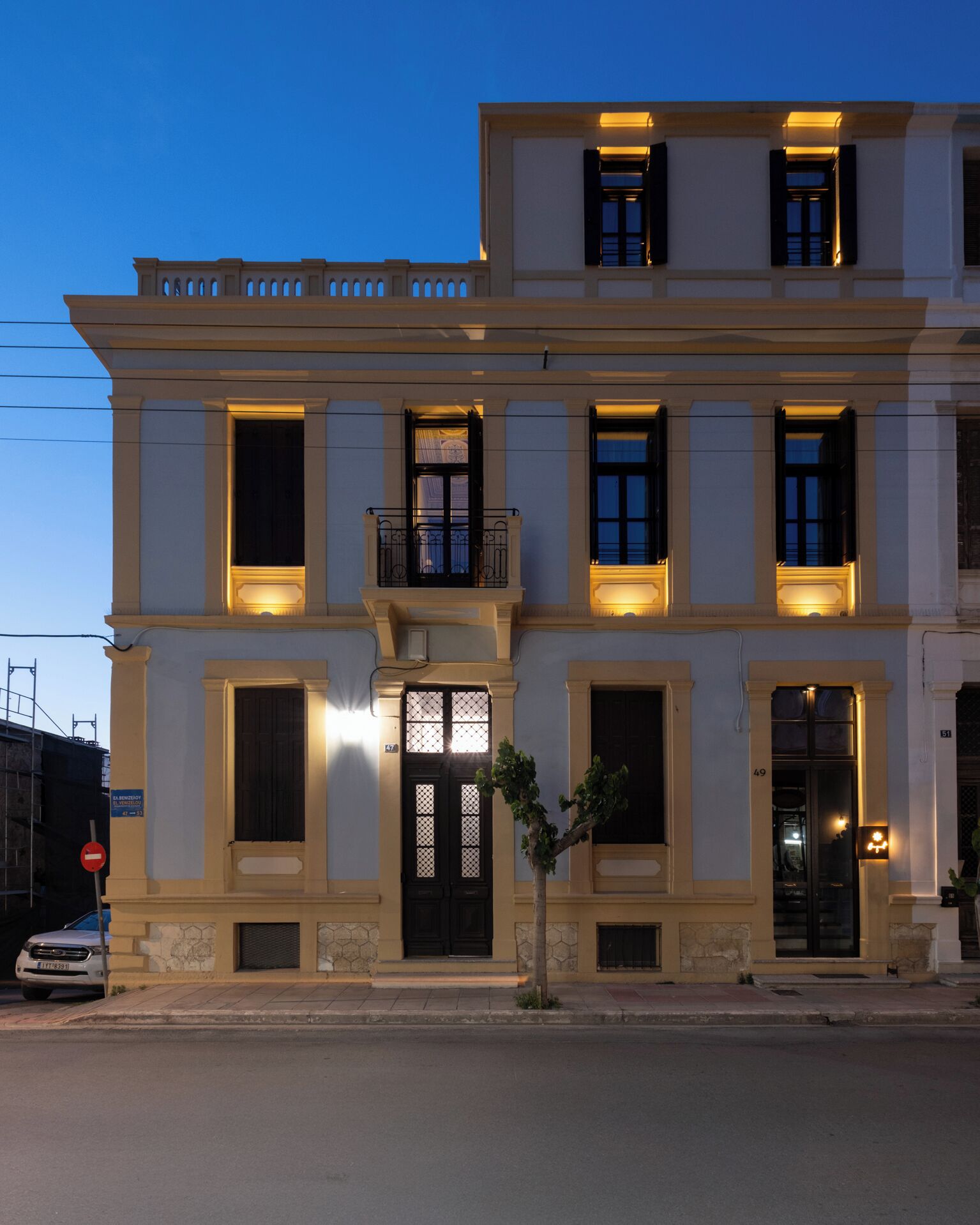Un edificio de dos plantas con fachada simétrica, que presenta una entrada central con una puerta decorativa y ventanas en ambos pisos.