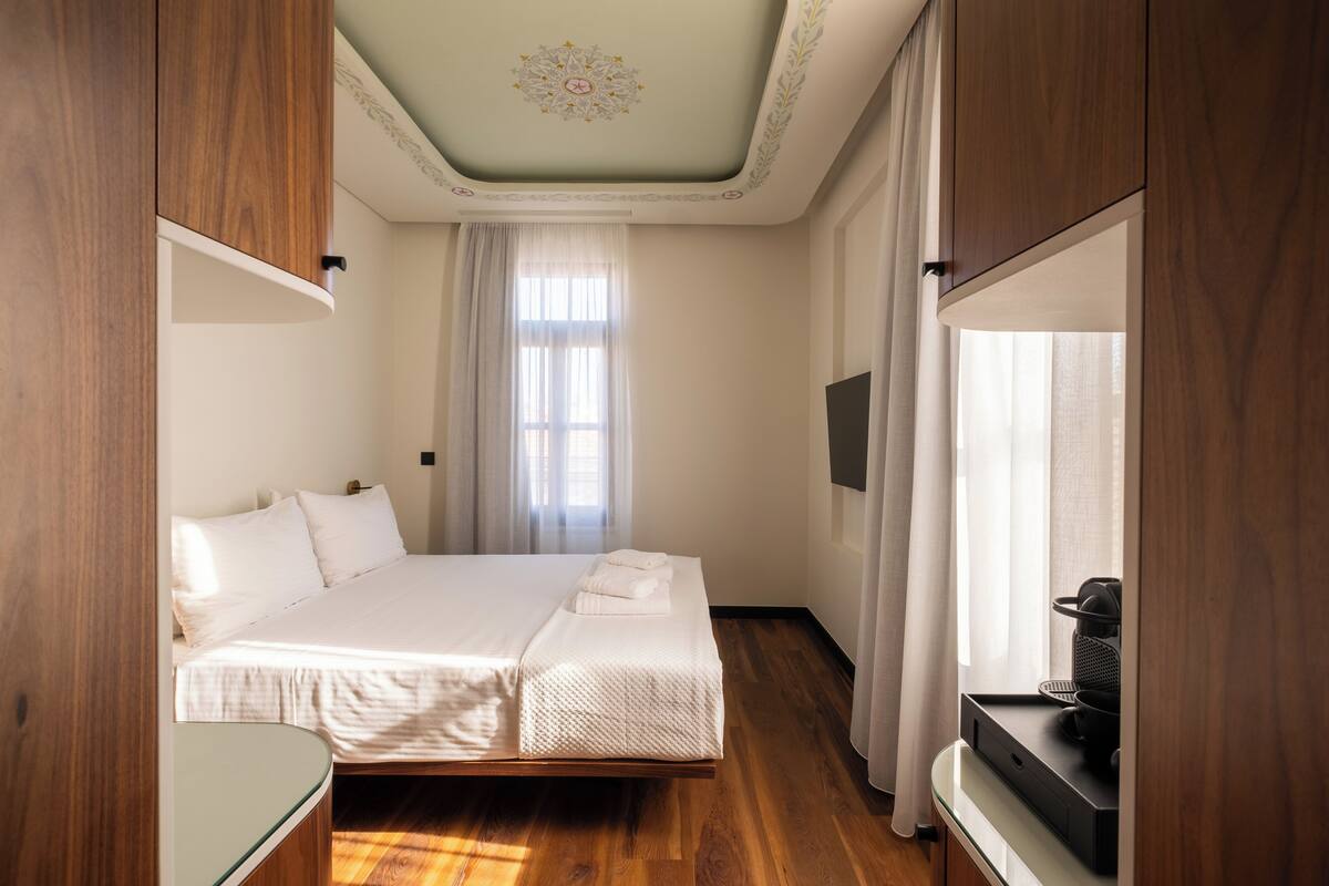 Quarto de hotel com cama, televisão e uma pequena mesa com uma cesta.