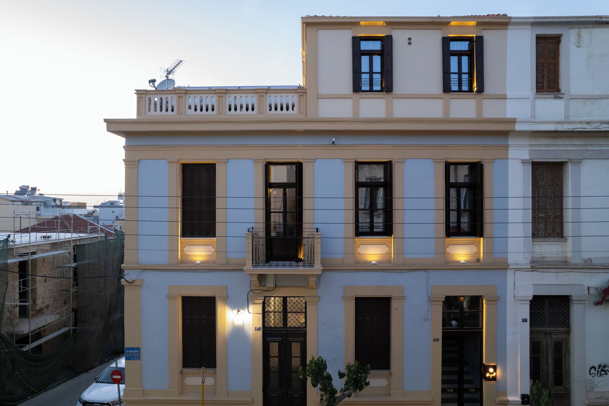 A multi-story building with a balcony on the second floor, a gated entrance, and a visible address number.