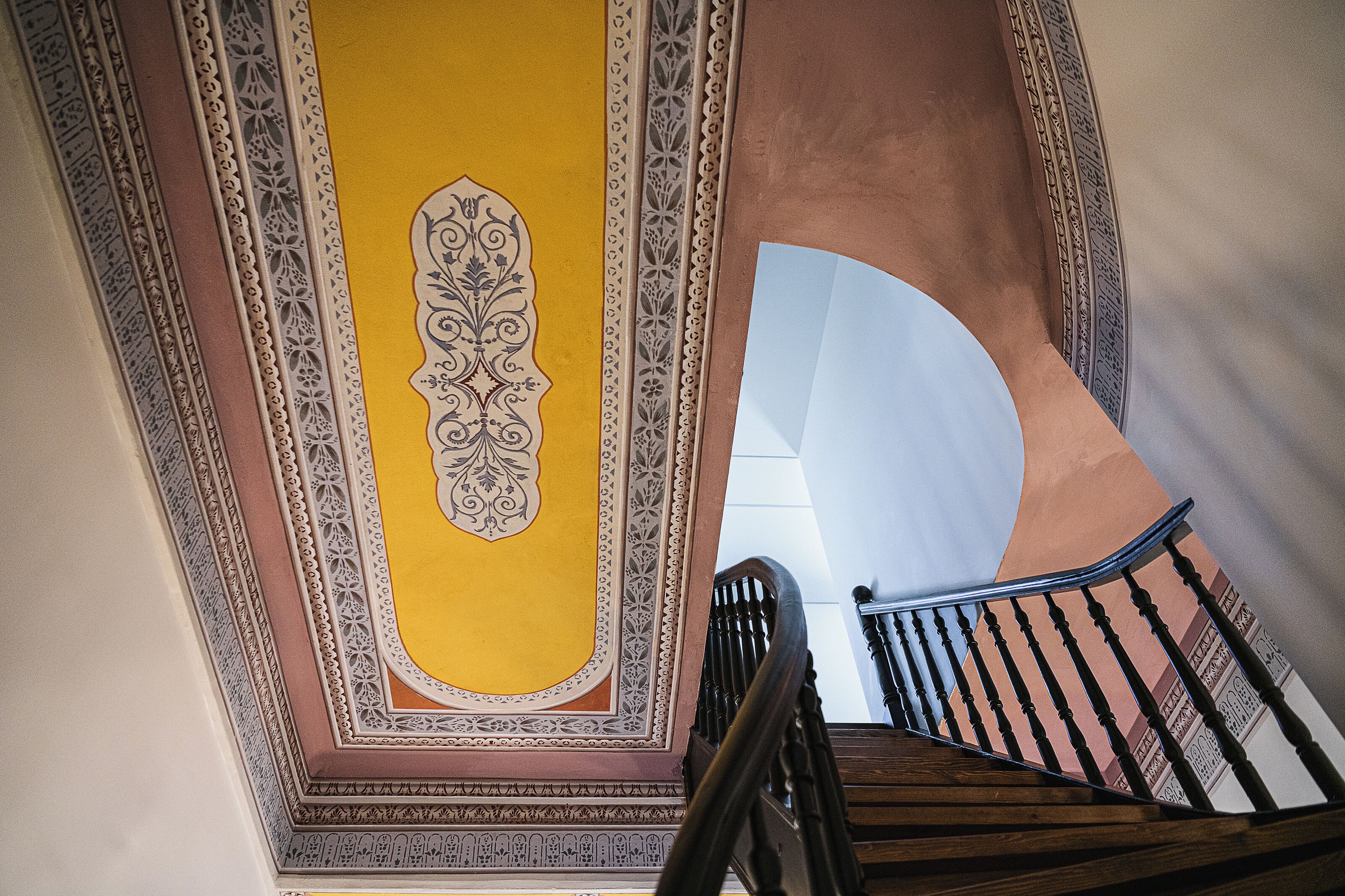 A staircase with ornate wall decorations and a wooden handrail.