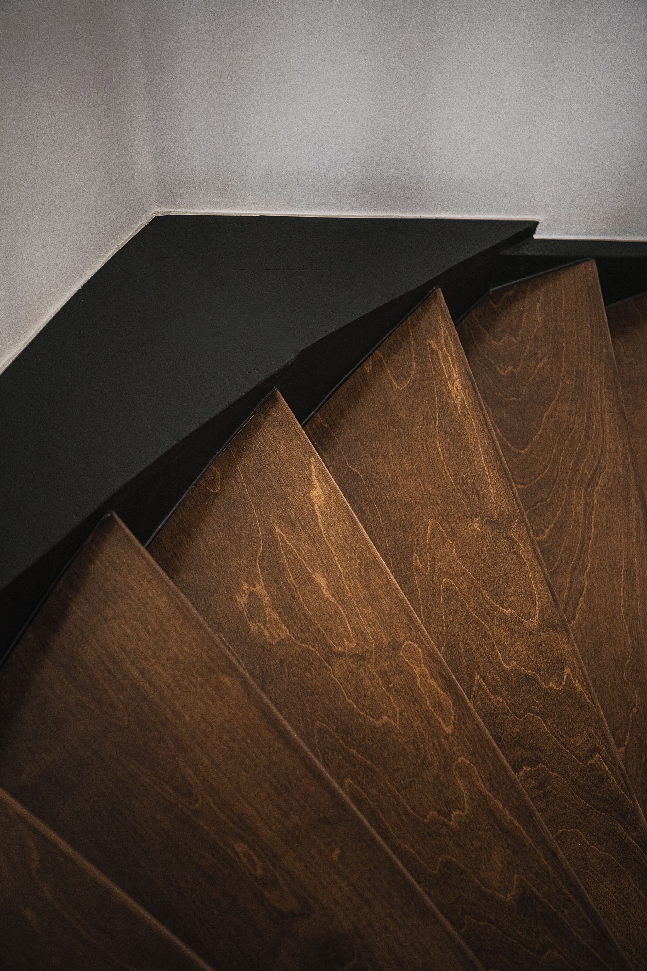 A staircase with wooden steps and a dark handrail.