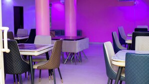 A modern dining area with tables and chairs, pink walls, and purple lighting. - New Eastern Comfort Hotel Umuahia (Umuahia)