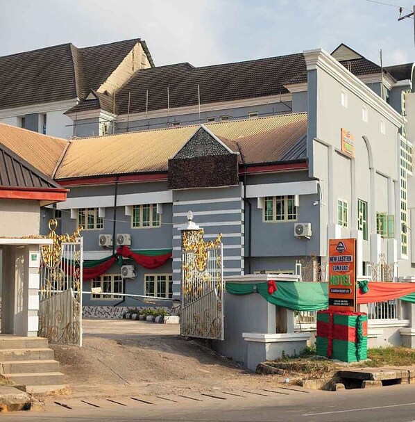 Un edificio con entrada protegida por una reja, unidades de aire acondicionado y un cartel que dice "New Eastern Comfort".