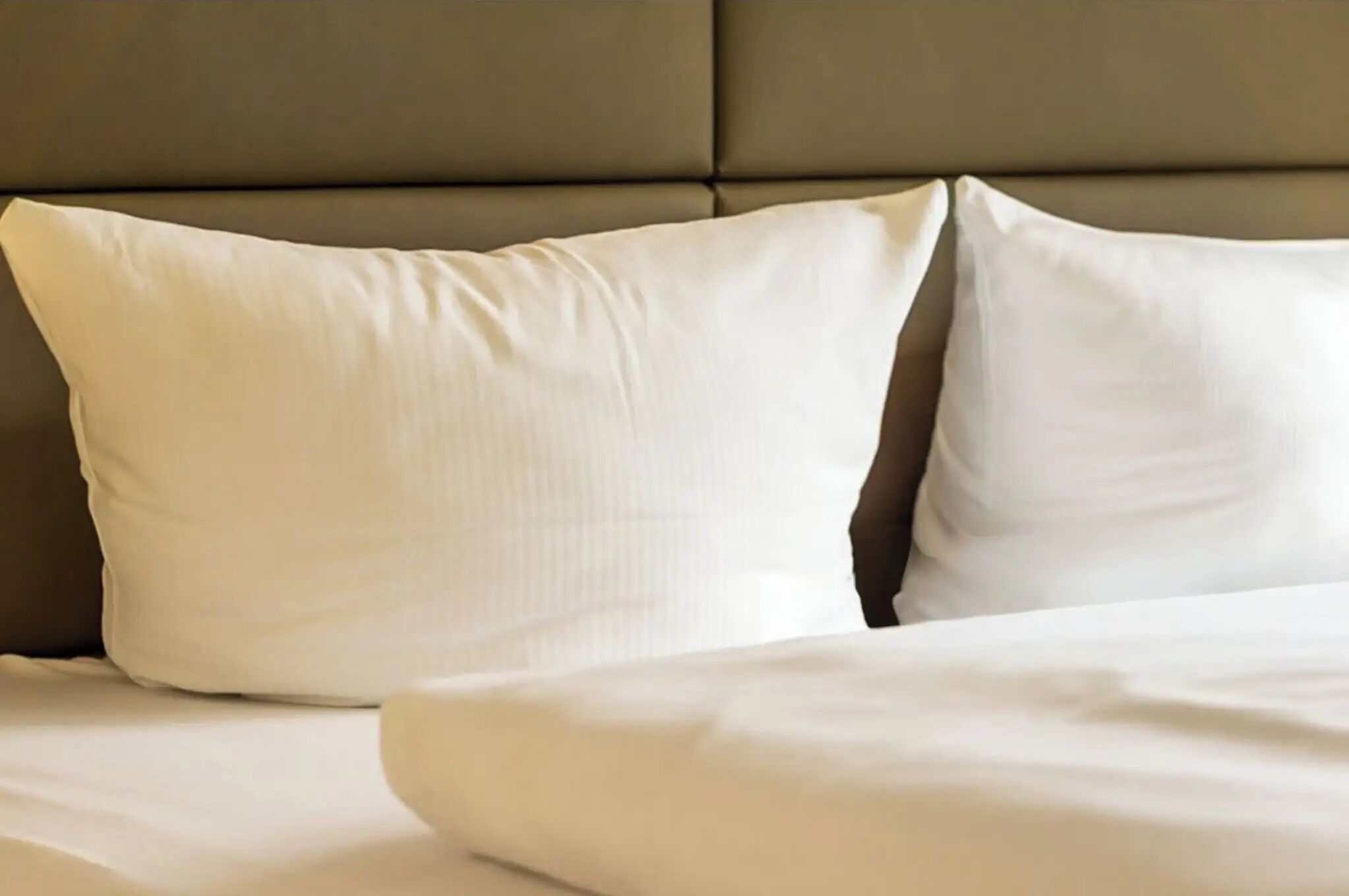A bed with white bedding and a headboard.
