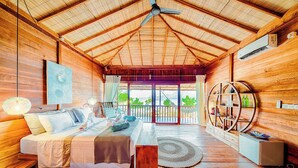 A wooden cabin with a bed, a chair, a round table, and a view of the outdoors. - Kuda Laut Boutique Dive Resort (Siladen Island)