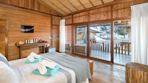 A wooden room with a bed, a small table, and a window. - Kuda Laut Boutique Dive Resort (Siladen Island)
