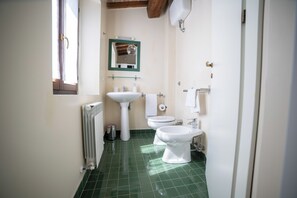 Un baño pequeño con un radiador, un lavabo, un inodoro y un bidé.