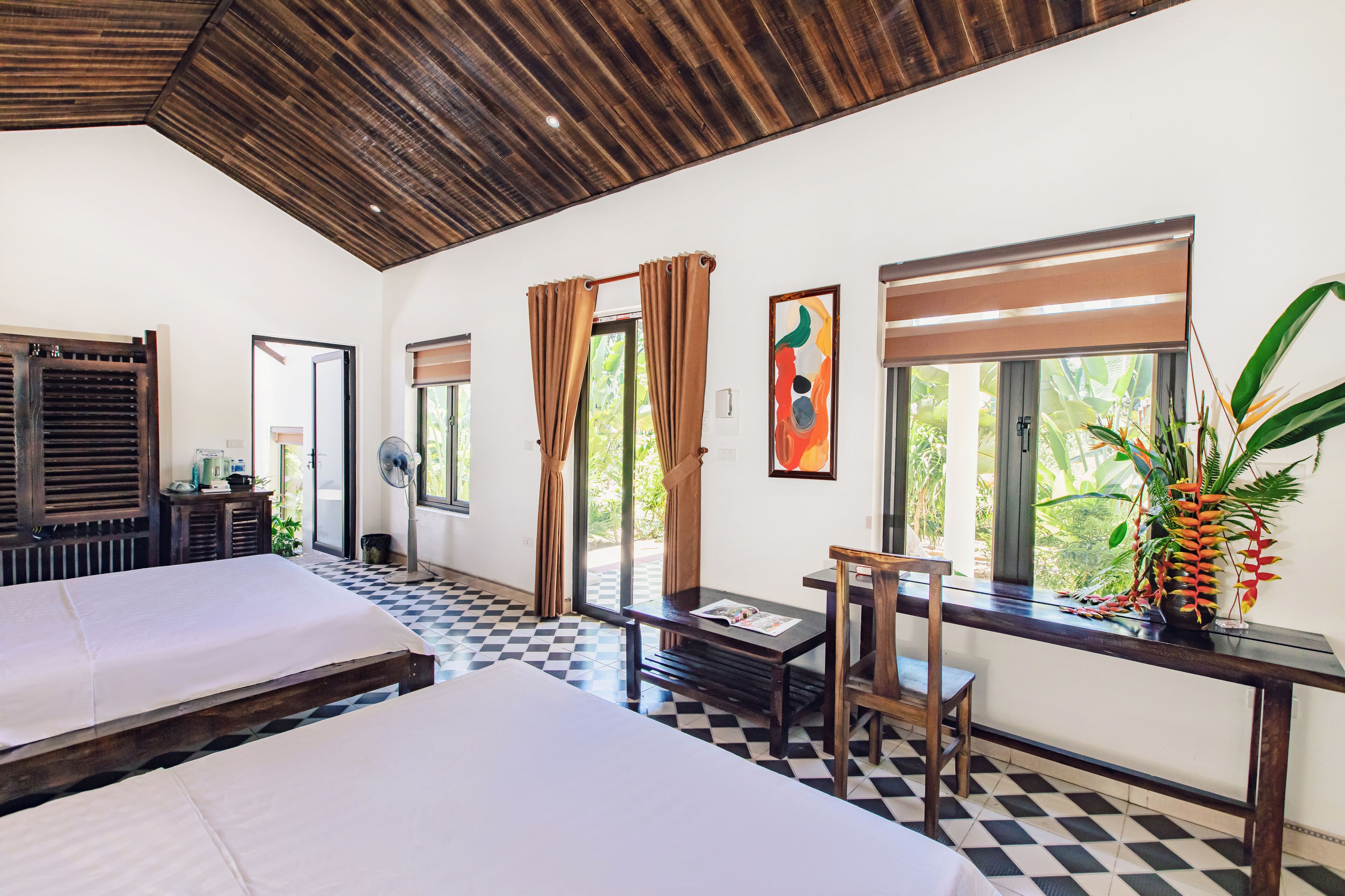 A hotel room with two beds, a checkered floor, a wooden ceiling, and large windows with curtains.