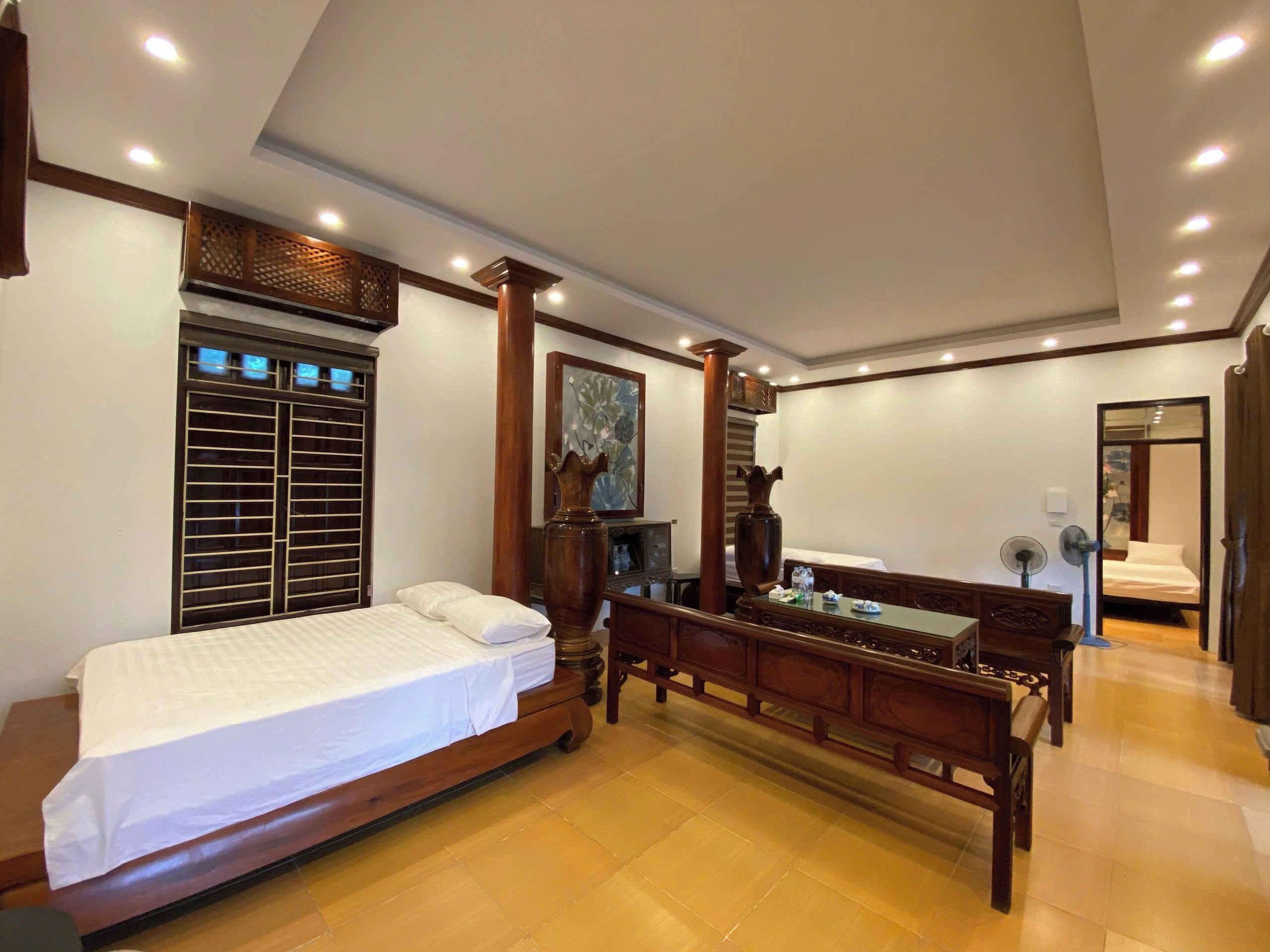 Un dormitorio con cama, muebles de madera, un jarrón grande y un cuadro en la pared.