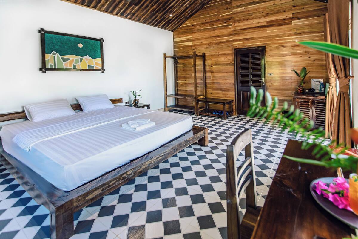 Ein Zimmer mit einem Bett, Holzwänden, einem karierten Boden und einem Gemälde an der Wand.