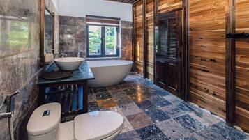 Un baño con una bañera independiente, un lavamanos y un inodoro.