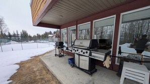 Une terrasse extérieure avec un barbecue, une petite table et un sol en béton.