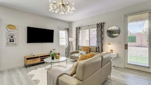 A modern living room with a beige sofa, a flat-screen TV, a wooden console table, and a round coffee table.