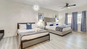 A bedroom with two beds, a ceiling fan, and a chandelier.