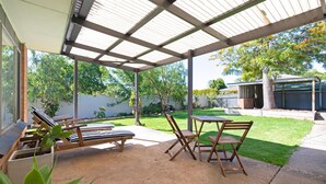 A covered patio with a table and chairs, a lounge chair, and a potted plant. - Brewers Haus ~ Willunga - A Newly Renovated Property In the Heart Of Willunga (Willunga)