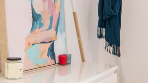 A room with a white dresser, a framed abstract painting, a wooden hanger with a dark blue garment, and a red candle. - Brewers Haus ~ Willunga - A Newly Renovated Property In the Heart Of Willunga (Willunga)