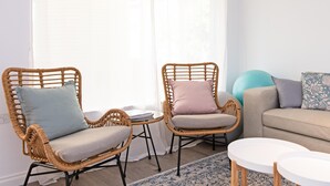 A living room with two wicker chairs, a small table, a sofa, and a patterned rug. - Brewers Haus ~ Willunga - A Newly Renovated Property In the Heart Of Willunga (Willunga)