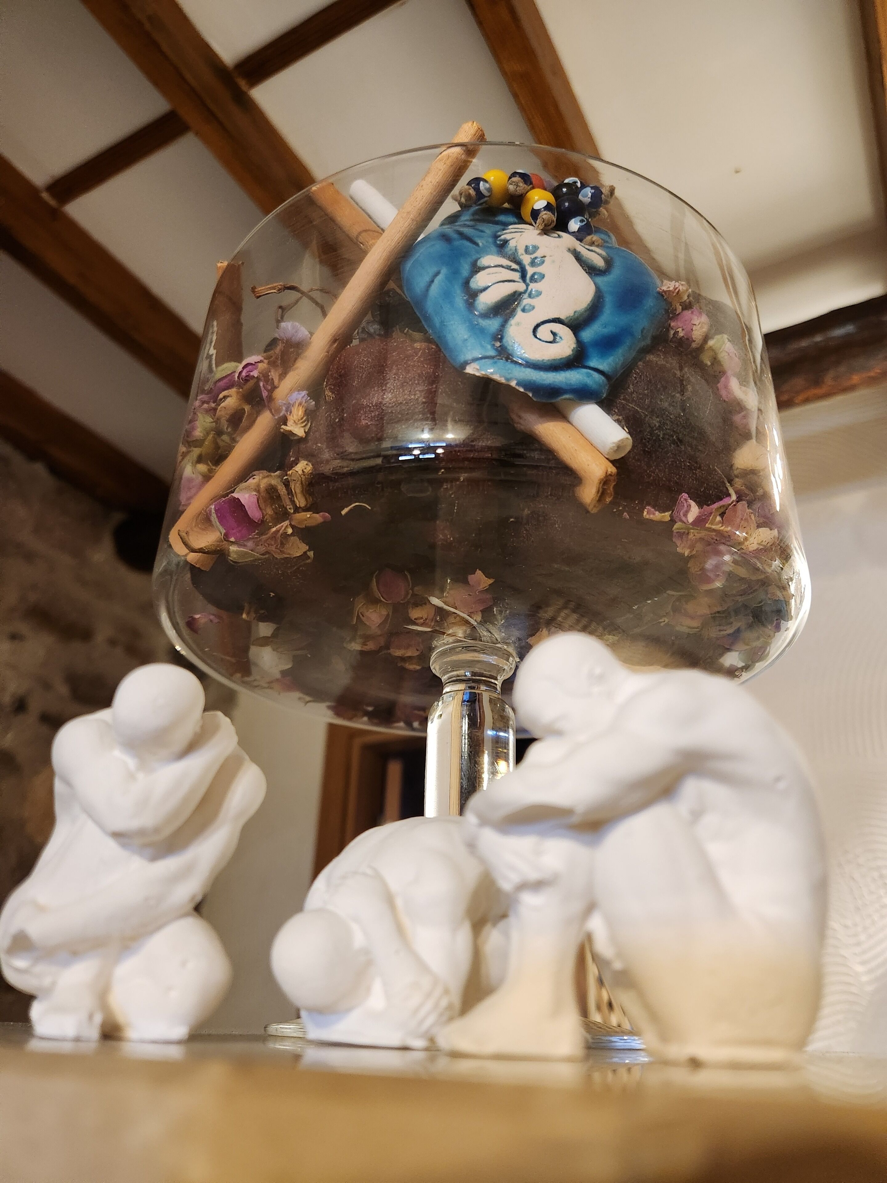 A glass vase with dried flowers and a blue decorative piece.