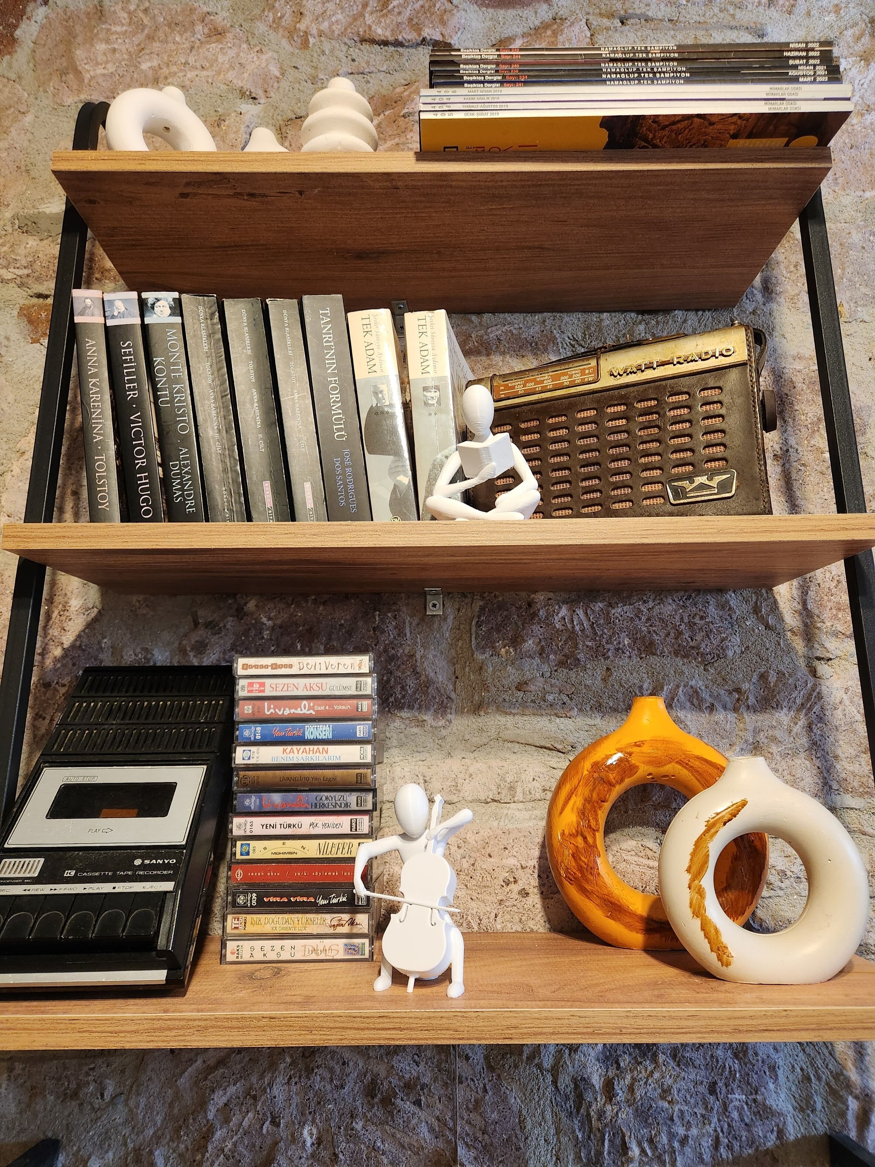 A wooden shelf with books, a cassette player, and decorative items.