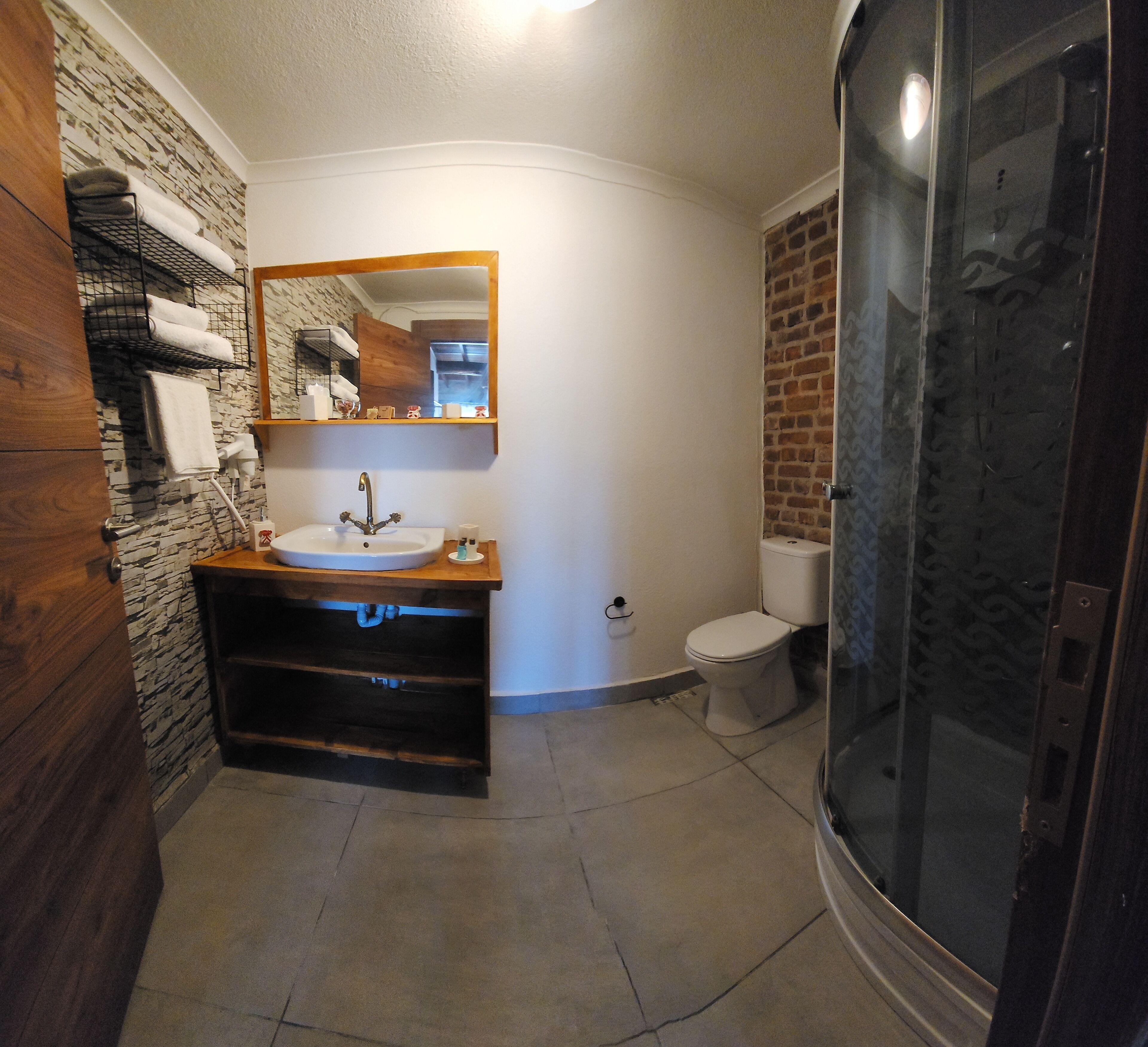 A bathroom with a wooden vanity, a white sink, a mirror, a toilet, and a shower enclosure.