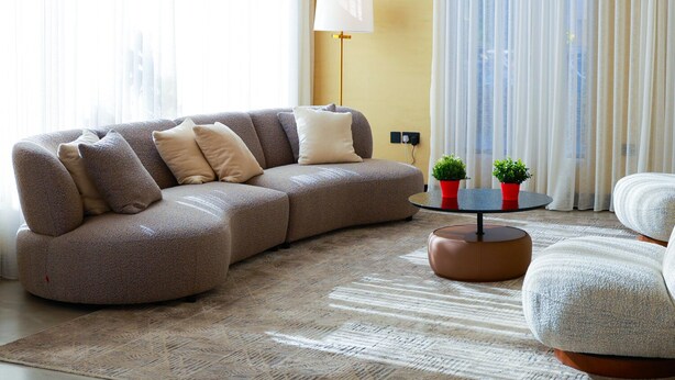 A modern living room with a sectional sofa, a round coffee table, and a floor lamp.