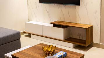 Una sala de estar moderna con una televisión de pantalla plana montada en la pared, una mesa de centro de madera y sofás grises.