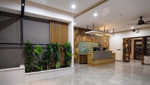 A modern reception area with a wooden reception desk, a large abstract painting, and a plant wall. - K2 Hotel by Green Pak Skardu (Skardu)