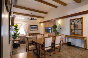 A dining area with a wooden table and chairs, a television mounted on the wall, and a window with curtains. - K2 Hotel by Green Pak Skardu (Skardu)