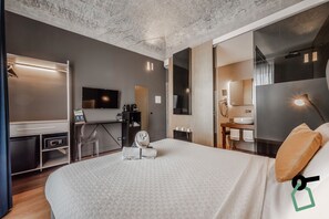 A modern hotel room with a large bed, a desk with a computer, a TV, and a bathroom with a sink and mirror. - Hotiday Palermo Palco Noir (Palermo)