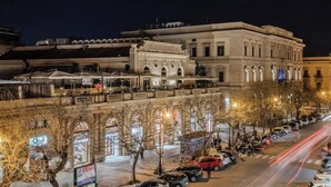 A nighttime cityscape with a historic building, parked cars, and a street lined with trees. - Hotiday Palermo Palco Noir (Palermo)