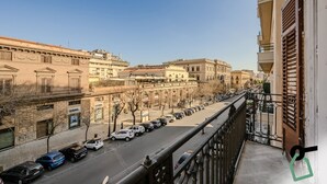 Udsigt fra en balkon over en by med parkerede biler og historiske bygninger.