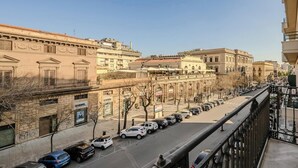 A street view from a balcony overlooking a cityscape with parked cars and historic buildings. - Hotiday Palermo Palco Noir (Palermo)