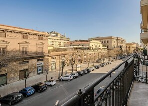 A street view from a balcony overlooking a cityscape with parked cars and historic buildings. - Hotiday Palermo Palco Noir (Palermo)