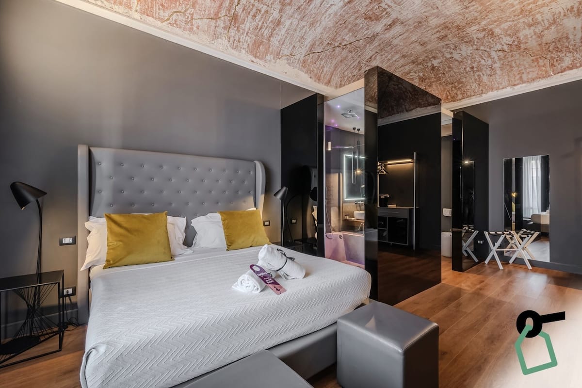 A modern bedroom with a large bed, bedside tables, a desk, and a mirror.