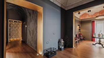 Interior moderno com piso de madeira, design geométrico na parede e área de estar com mesa e cadeiras.