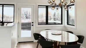 A modern dining area with a round table, black chairs, and a chandelier.
