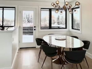 Un comedor moderno con una mesa redonda, sillas negras y una araña.